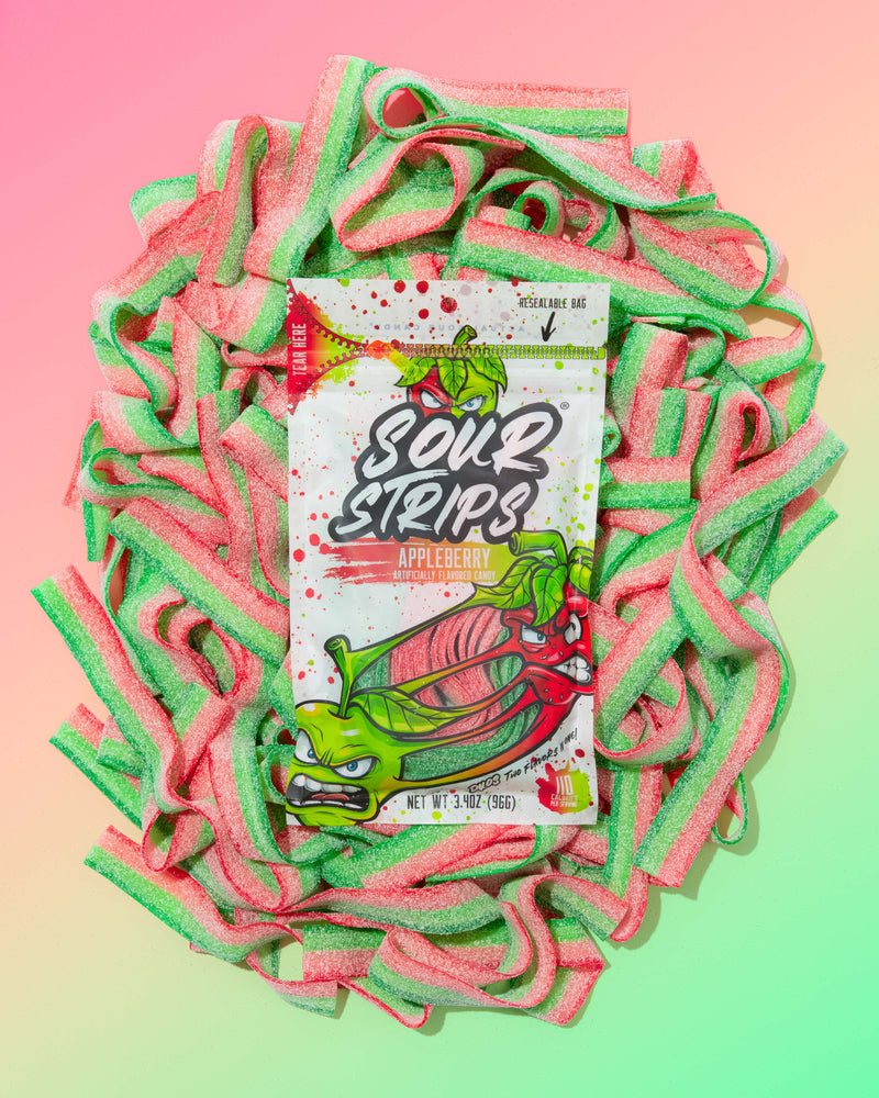 A Duos Sampler-Six Pack from SourStrips sits in the center, surrounded by loose red, green, and white sour candy strips against a pastel gradient background. The packaging features illustrated fruit characters, hinting at unique flavors.