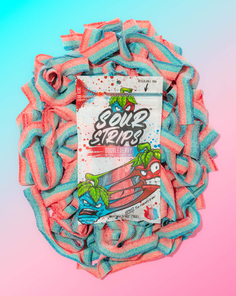 A Duos Sampler-Six Pack from SourStrips sits atop a pile of red and blue sugar-coated sour strips, set against a pastel pink and blue gradient background, showcasing these exciting limited edition flavors.