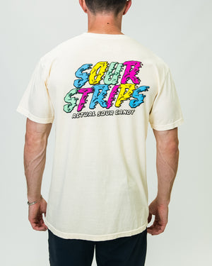 A person is seen from the back wearing an oversized box fit, Melted Tee from SourStrips in a light color, adorned with colorful, graffiti-style text that reads "Sour Strips" and "Actual Sour Candy." The unisex design shirt and individual are set against a plain white background.