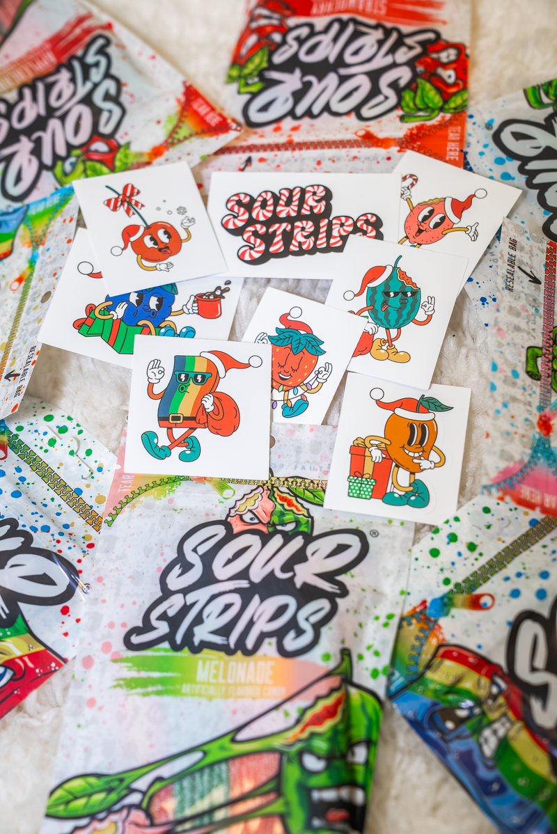 The SourStrips Holiday Gift Box-Fourteen Pack features colorful candy packages and festive cartoon stickers with Christmas designs—perfect for gifting or collecting these limited edition holiday-themed treats.