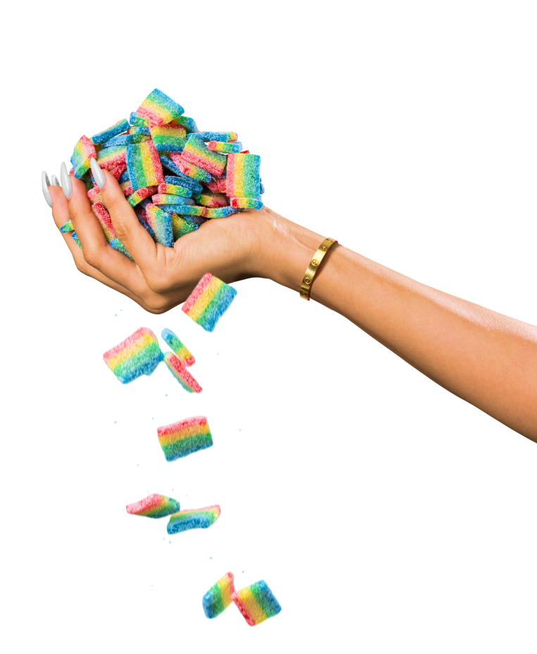 A hand with a gold bracelet and manicured nails holds a colorful heap of rainbow-striped gummy candies, some of which are falling in mid-air. The background is transparent, emphasizing the vibrant colors of the candies.