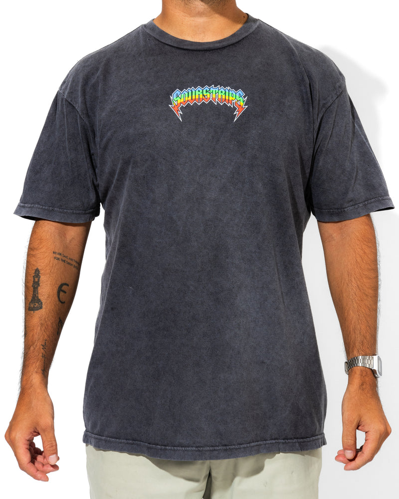 A person wears the SourStrips Sour Storm Tee—a faded black graphic T-shirt with a colorful “LIVING STONES” logo—paired with light pants, a silver watch, and visible tattoos. Perfect for unisex cotton shirt fans.