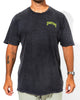 A person wearing a faded black SourStrips Twisted Temptation Tee with yellow-green chest text, light pants, a watch, and visible arm tattoos stands against a white background. This unisex cotton tee adds bold style to any outfit.