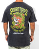 A person wearing the SourStrips Twisted Temptation Tee, a black unisex cotton shirt with a colorful skull, strawberries, and green vines on the back, and text reading "Sourstrips Sour Candy to Die For" and "Actual Sour Candy.