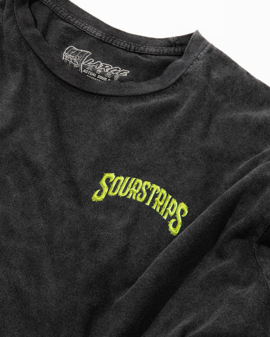 The SourStrips Twisted Temptation Tee is a black unisex cotton shirt featuring bold yellow-green "SOURSTRIPS" text on the chest, with "LARGE" and "A CULTURE DRIP" on the collar tag, laid flat on a white surface.