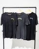 Three black SourStrips Sour Storm Tees with unique graphics hang on wooden hangers from a black rack, showcasing the perfect unisex cotton style against a crisp white background.
