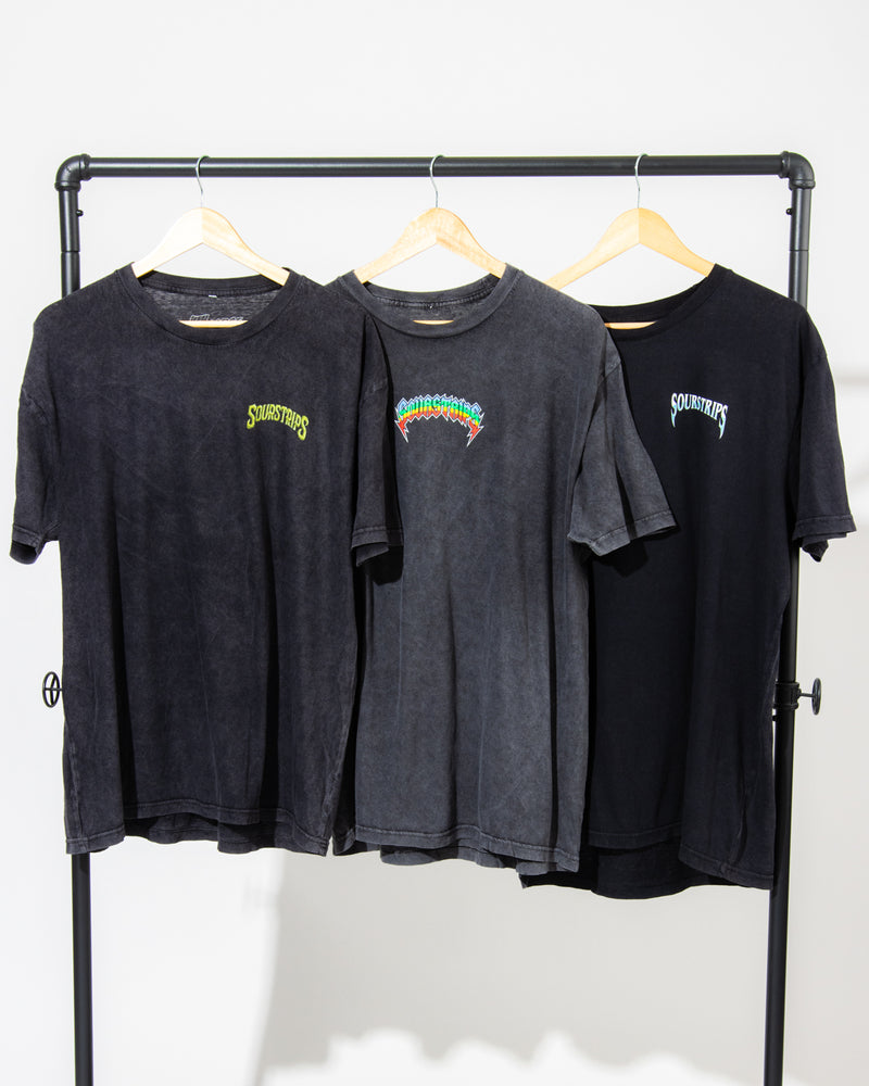 Three black unisex cotton Twisted Temptation Tees by SourStrips hang on wooden hangers from a metal rack. Each sports a vibrant "Sourcefurs" logo on the left chest, set against a plain white background to highlight these graphic T-shirts.
