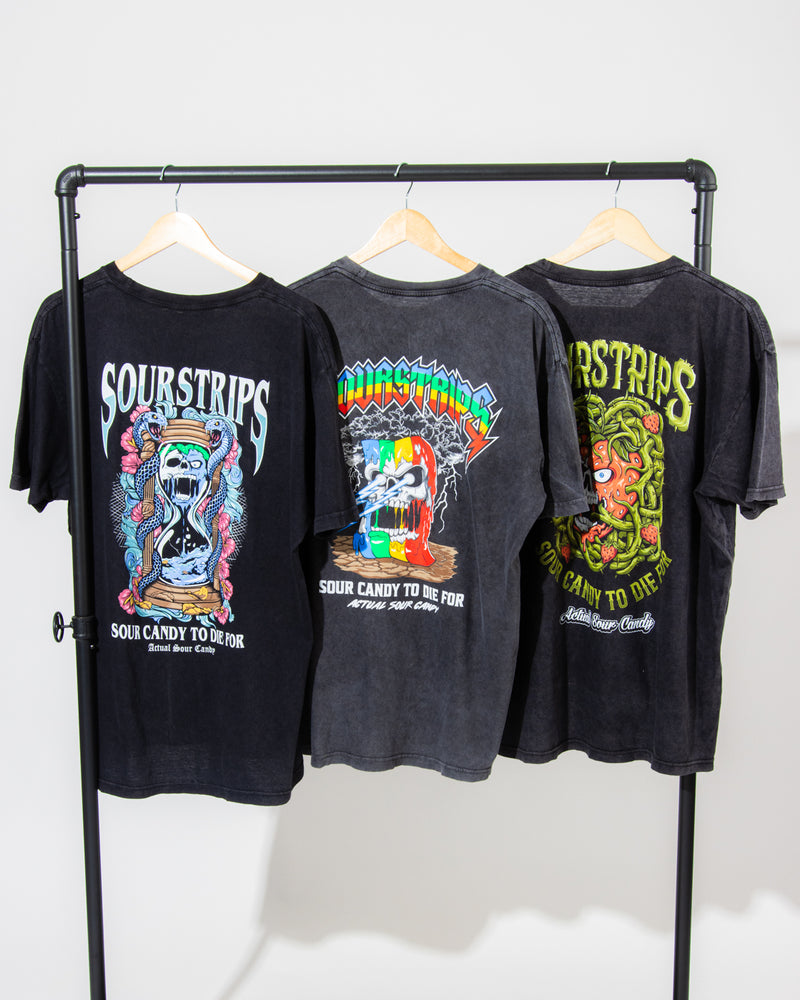 Three unisex SourStrips Sour Storm Tees hang on a rack, each featuring vibrant artwork. The back of these cotton graphic T-shirts displays "Sour Strips" and the slogan "Sour Candy to Die For.
