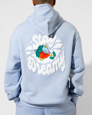 Someone wears the SourStrips Dreamberry Hoodie, a unisex cotton hoodie featuring a vibrant illustration of a strawberry sleeping on a cloud and "Stay Dreamy" in bold white letters on the back.