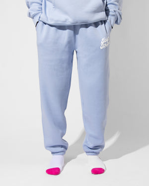 A person models SourStrips Dreamberry Joggers with a matching sweatshirt, standing on a white floor. Their lower half is shown, wearing white socks with bright pink toes.