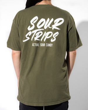 Individual with long hair wearing a SourStrips Logo Tee - Green, featuring white text that reads "Sour Strips" and "Actual Sour Candy" on the back, standing against a plain white background. The unisex design of this trendy, casual tee ensures broad appeal.