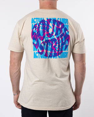 A person is wearing the trendy Vortex Tee by SourStrips, an oversized beige t-shirt with a large, colorful graphic on the back. The super soft cotton tee showcases a wavy, vibrant design in blue and pink with the text "ACTUALLY SOUR CANDY" repeated multiple times. The person is facing away from the camera.
